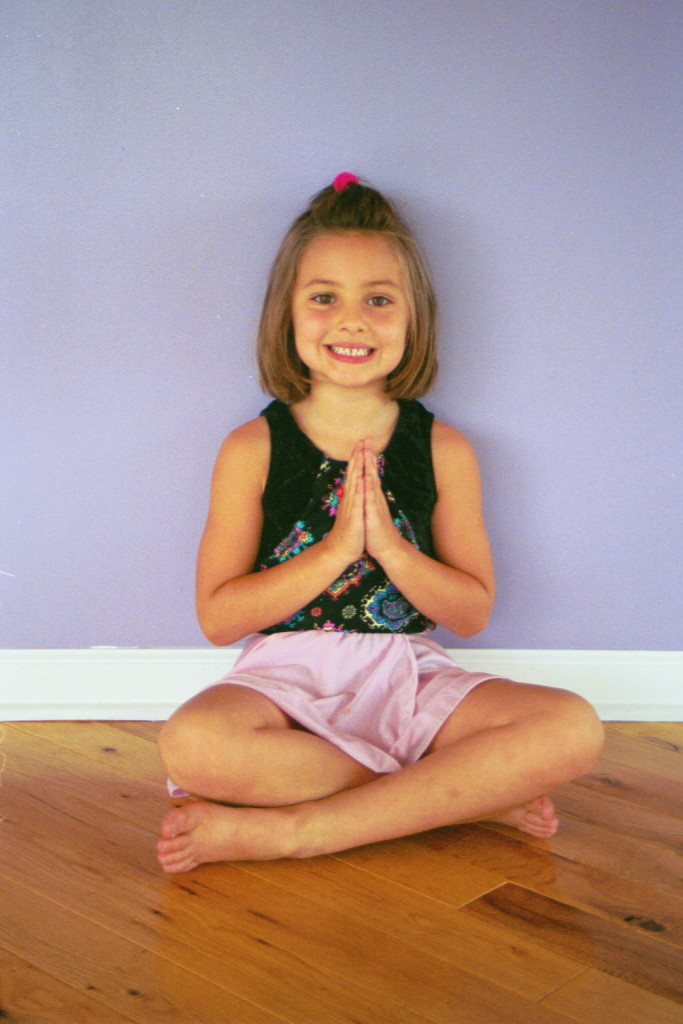 Child sitting with legs crossed and hands at center of chest