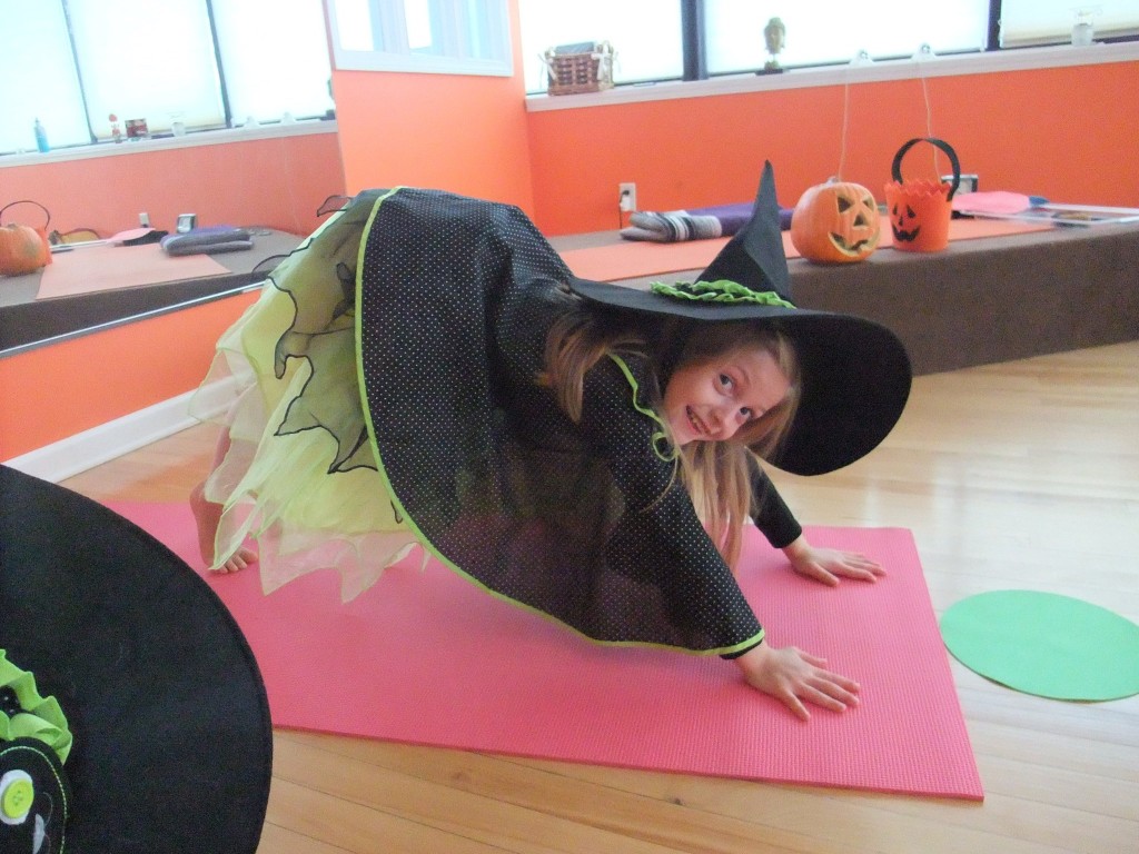 child dressed as witch and on yoga mat